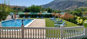 una piscina con sillas y sombrillas y una valla blanca en La Casita de Rufo, en Granada