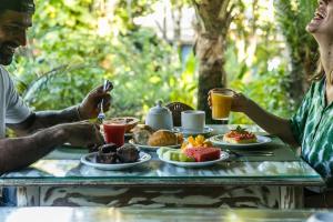 Um homem e uma mulher sentados à mesa com comida. em Pousada do Bosque em Trancoso