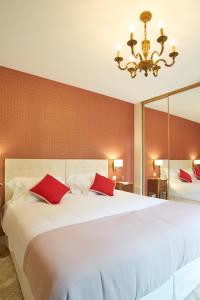 a bedroom with a large white bed with red pillows at Chateau Pont Saint-Martin in Léognan