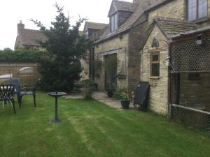 a garden with a table and chairs in a yard at Robinas Cotswold Coach House in Witney