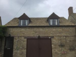 two windows on the roof of a brick house at Robinas Cotswold Coach House in Witney