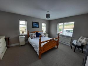 um quarto com uma cama de madeira e 2 janelas em Island View Bed and Breakfast em Doolin