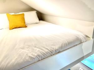 a white bed with a yellow pillow on it at Apartment @ Bastion Mews in Hereford