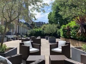 patio z krzesłami, stołami i drzewami w obiekcie Nevern Place by Supercity Aparthotels w Londynie
