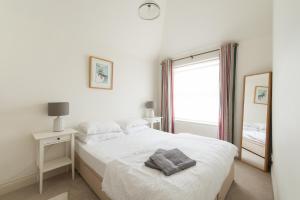 a white bedroom with a bed and a mirror at My Place Go - Cirencester in Cirencester
