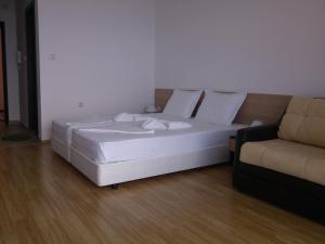 a white bed in a room with a couch at Villa Lazuren Bryag 2 in Chernomorets