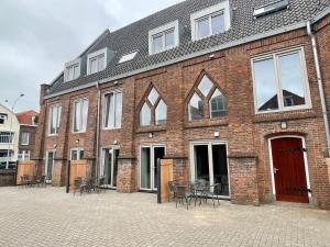 un bâtiment en briques avec des tables et des chaises devant lui dans l'établissement Woonhotel Petruskerk, à Flessingue