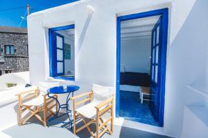 a balcony with a blue door and chairs and a table at Blue Moon Villa in Imerovigli