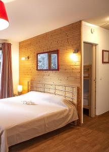 1 dormitorio con 1 cama con pared de madera en Le Hameau SPA & PISCINE studio 4pers by Alpvision Résidences, en Orelle