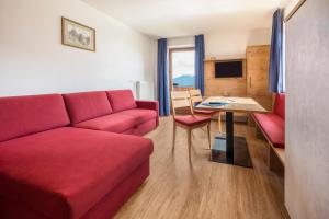 Una sala de estar con un sofá rojo y una mesa. en Residence Condor Apt Rosengarten, en Maranza