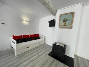 Habitación blanca con sofá y almohadas rojas. en El secret de la LLegenda El Cavaller en Vilavert