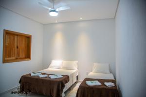 a room with two beds and a ceiling fan at Pousada Império de Minas in Capitólio