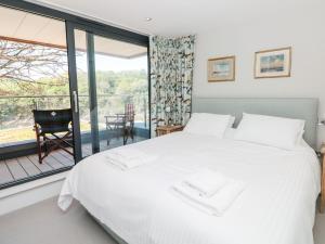 a bedroom with a white bed and a balcony at 3 The Hide in Plymouth