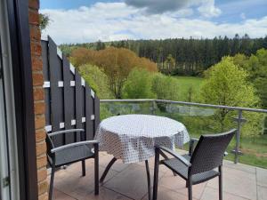 een tafel en stoelen op een balkon met uitzicht bij Ferienwohnung Mossauer Hoehe in Mossautal