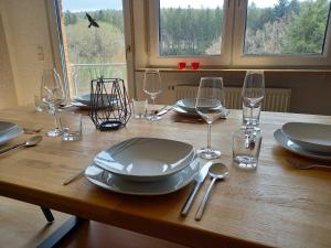 a wooden table with plates and wine glasses on it at Ferienwohnung Mossauer Hoehe in Mossautal