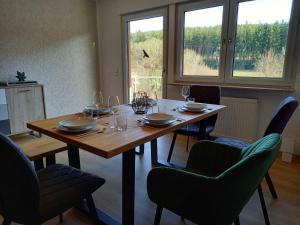 a wooden table with chairs and wine glasses on it at Ferienwohnung Mossauer Hoehe in Mossautal