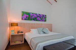 1 dormitorio con 1 cama con flores púrpuras en la pared en Hotel Recinto Quirama - Comfenalco Antioquia, en San Antonio de Pereira