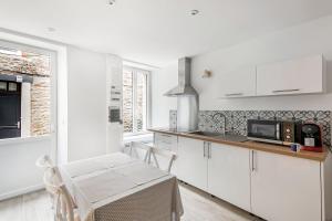 uma cozinha com armários brancos e uma mesa e cadeiras em Le Coco - Duplex proche mer em Cancale