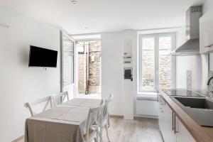 uma cozinha com uma mesa e cadeiras e uma televisão em Le Coco - Duplex proche mer em Cancale