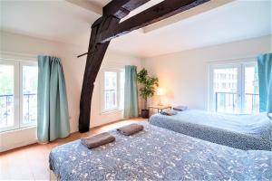 two beds in a room with two windows at The Central Square Residence in Antwerp