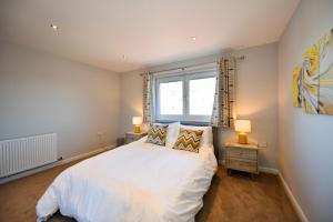 1 dormitorio con cama blanca y ventana en Troon Executive Apartment, en Troon