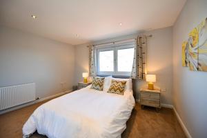 a bedroom with a white bed and a window at Troon Executive Apartment in Troon