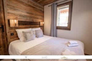 a bedroom with a white bed with a wooden wall at MARMOTTE 101 - Appartement pour 6, aux pieds des pistes in Bonneval-sur-Arc