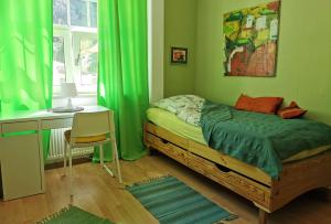 Schlafzimmer mit grünen Vorhängen und einem Bett mit einem Schreibtisch in der Unterkunft Ferienwohnung in idyllischer Lage in Sauerthal