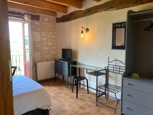 a bedroom with a bed and a desk with a television at Logis Auberge de Crissay in Crissay-sur-Manse