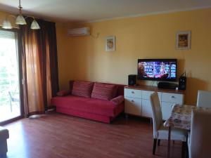 Una sala de estar con un sofá rojo y un televisor de pantalla plana. en Coke Wellness Apartman, en Siófok