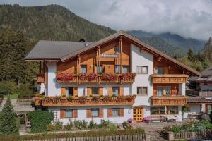 a building with a balcony with flowers on it at Residence Alpenrose in Rasùn di Sotto