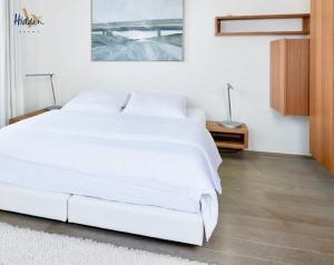 1 cama blanca grande en un dormitorio blanco en Hidden Bay Hotel en Cayeux-sur-Mer