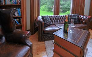 a living room with leather couches and a bottle of wine at Isla Bank House in Keith