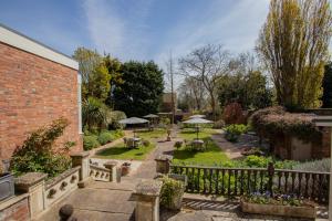 a garden with tables and umbrellas in a yard at Cley Hall in Spalding