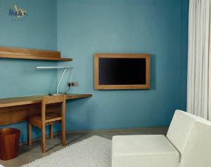 a blue room with a desk and a tv on a wall at Hidden Bay Hotel in Cayeux-sur-Mer