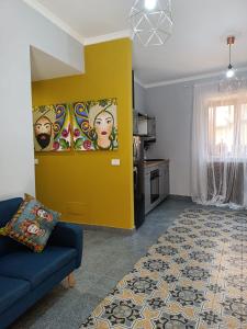 a living room with a blue couch and a yellow wall at A Cantunera LittleHouse in Agrigento
