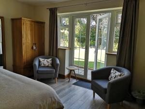a bedroom with a bed and two chairs and windows at White Cottage B and B in Spilsby
