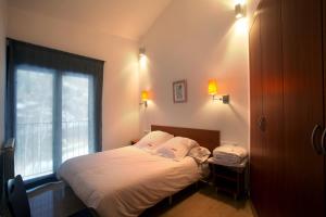 a small bedroom with a bed with a window at Apartaments Turístics Prat de Les Mines in Ordino