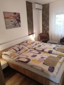 um quarto com uma cama grande e um edredão colorido em Anita Apartman em Bük