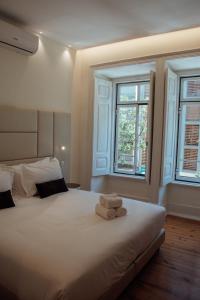 a bedroom with a large white bed with towels on it at Le Premier Lisbon Suites in Lisbon
