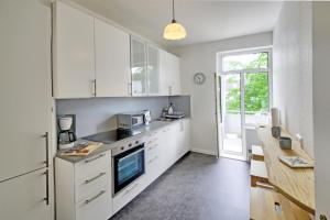 フレンスブルクにあるfewo1846 - Parkblick - komfortable Wohnung mit 2 Schlafzimmern und 2 Balkonenのキッチン(白いキャビネット、カウンタートップ付)