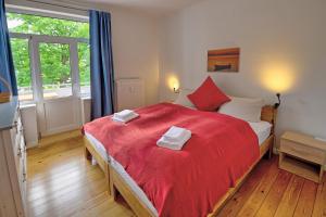フレンスブルクにあるfewo1846 - Parkblick - komfortable Wohnung mit 2 Schlafzimmern und 2 Balkonenのベッドルーム1室(大型赤いベッド1台、タオル付)