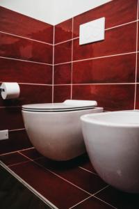 baño con aseo blanco y azulejos rojos en B&B BAGOLARI, en Villaganzerla