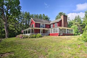 a red house on a grassy hill with trees at Vintage Schroon Lake Farmhouse w/ Private Beach! in Schroon Lake