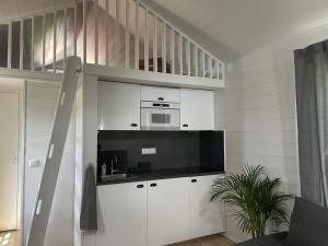 a living room with white cabinets and a microwave at Mini Villa Stockholm Älvsjö S61 in Stockholm