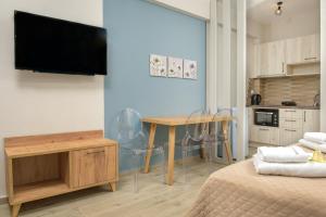 a living room with a table and a tv on a wall at ROUTE DU CANAL in Nea Roda
