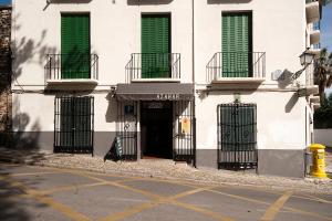 un edificio blanco con ventanas verdes y una puerta en casa carmen alhambra, en Granada