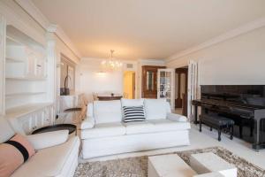 a living room with a white couch and a piano at BELLA VISTA LUXURY APARTMENT. BAY VIEWS. PARKING in San Sebastián