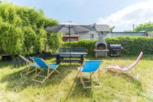 a group of chairs and a picnic table with an umbrella at Apartamenty Mewa in Rewa