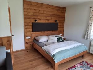 een slaapkamer met een bed met een houten muur bij Naturidyll Brunner in Köstendorf